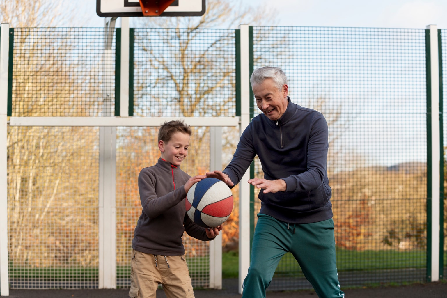 A grandfather and grandson playing basketball together outdoors